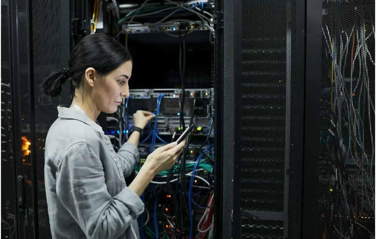 Technician working in a data center managing fiber optic connections, illustrating multimode fiber infrastructure and OM1 vs OM3 network performance in commercial environments
