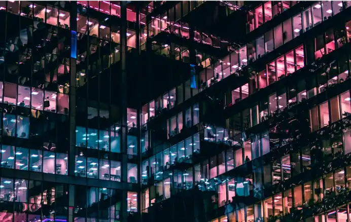 Modern office building with illuminated windows representing large commercial networks where LAN cable distance and Ethernet cable length limits affect structured cabling performance