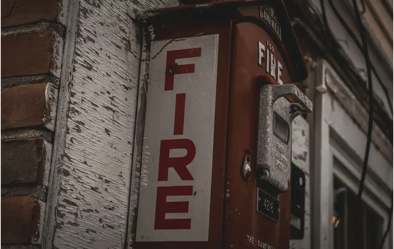 Exterior fire alarm call box mounted on building representing life safety communication systems supported by 2-hour fire alarm cable and circuit integrity wiring