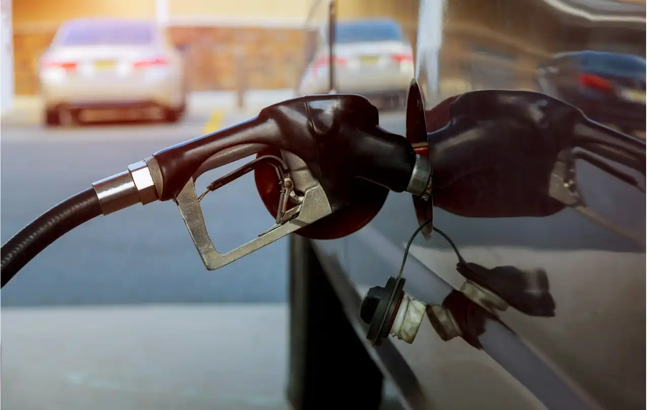 Fuel pump nozzle dispensing gasoline into vehicle, illustrating petroleum environments where cable ratings and oil-resistant construction support fuel system safety