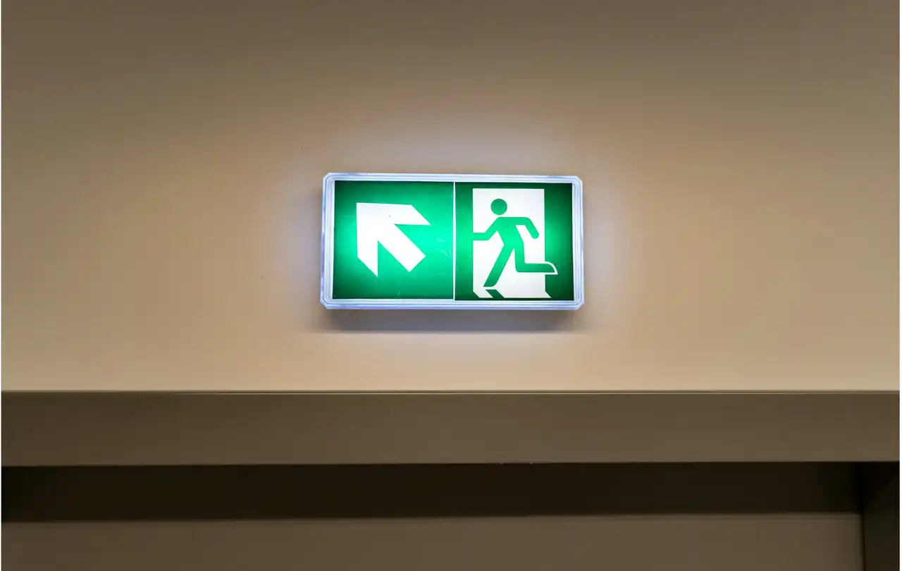 Illuminated emergency exit sign in commercial building, illustrating life safety systems that rely on 2-hour fire rated cable for circuit integrity during emergencies