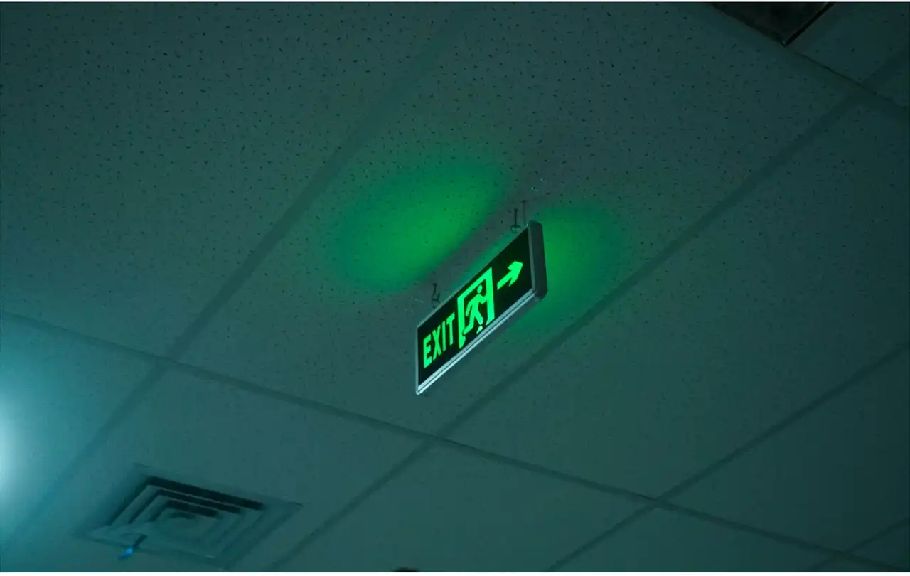 Green illuminated emergency exit sign in a commercial building, representing life-safety systems supported by 2 hour fire cable and fire rated cable