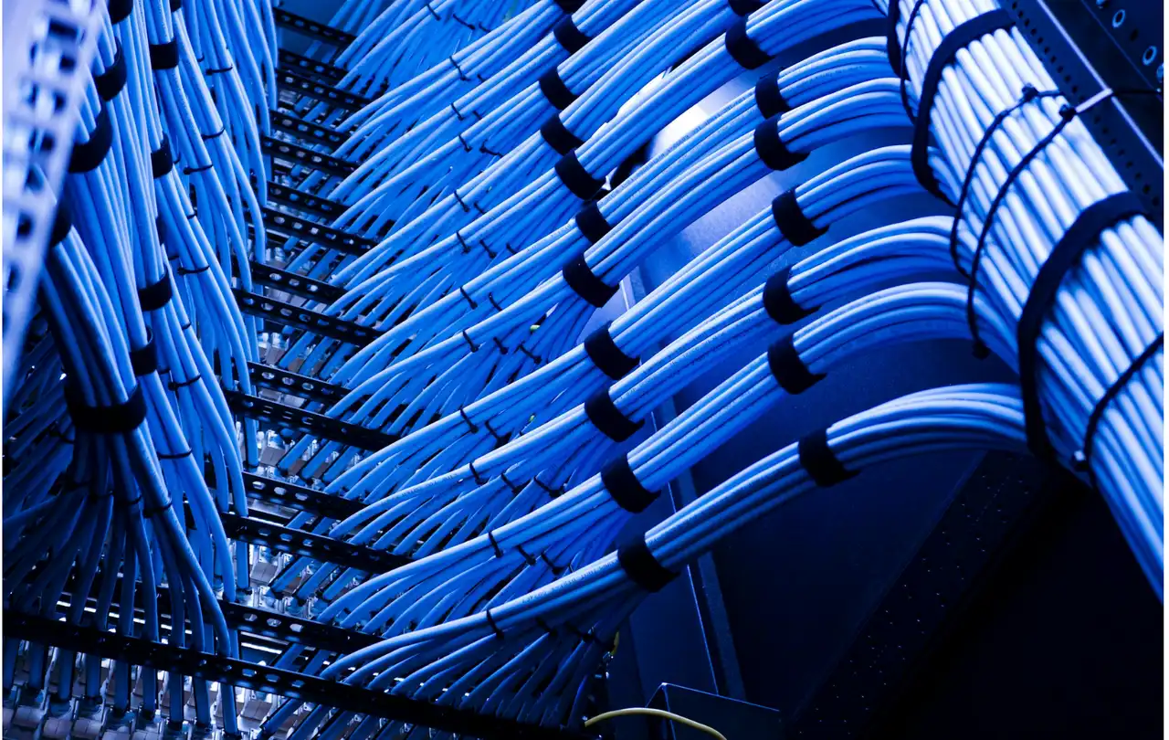 Organized Ethernet cable bundles in network rack, illustrating structured cabling systems where connectors and cable segments impact overall channel performance