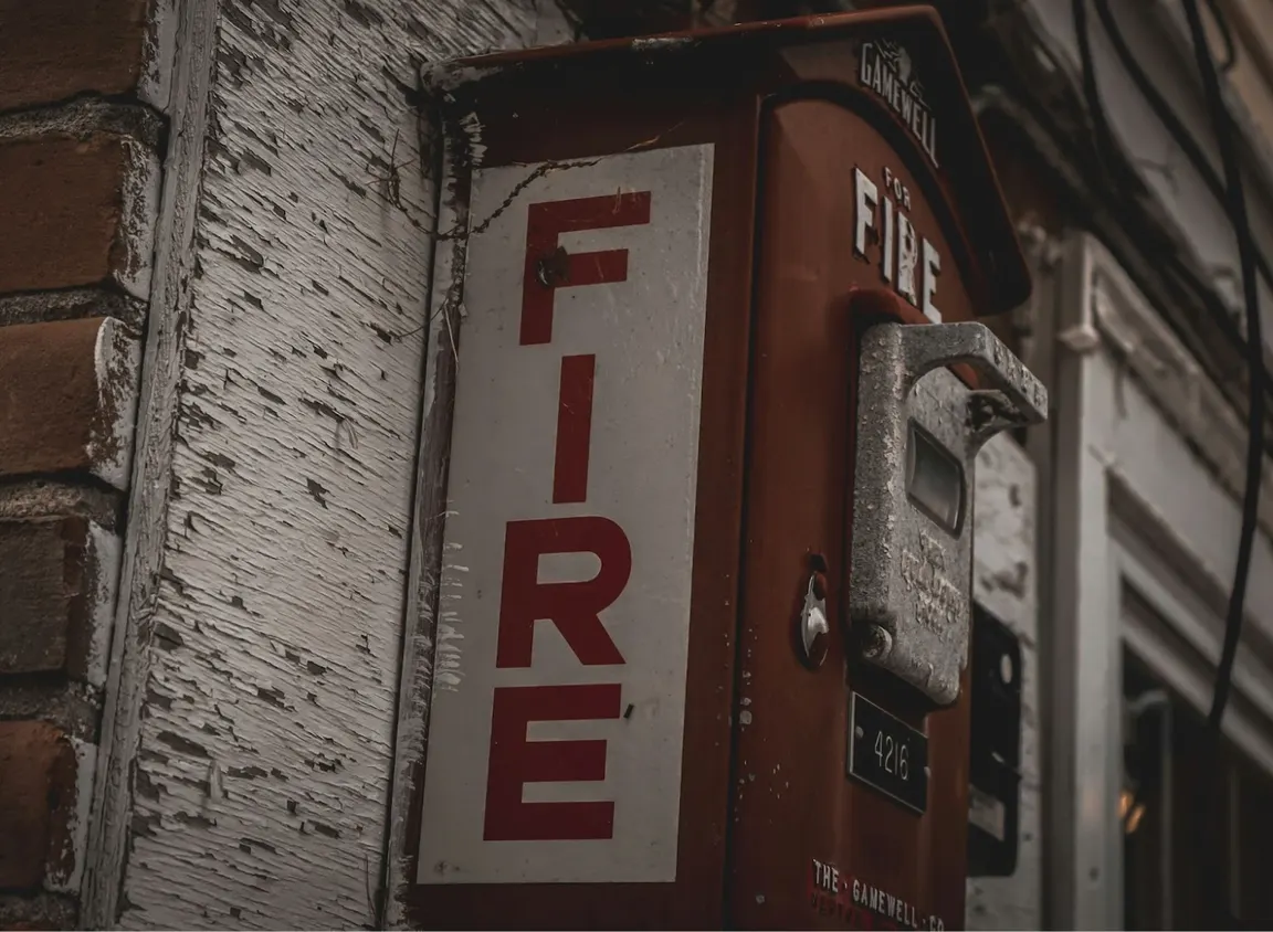 Exterior fire alarm call box mounted on building representing life safety communication systems supported by 2-hour fire alarm cable and circuit integrity wiring