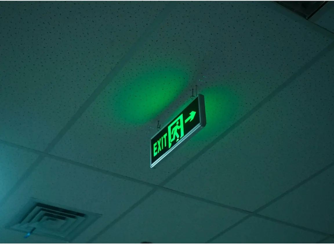 Green illuminated emergency exit sign in a commercial building, representing life-safety systems supported by 2 hour fire cable and fire rated cable