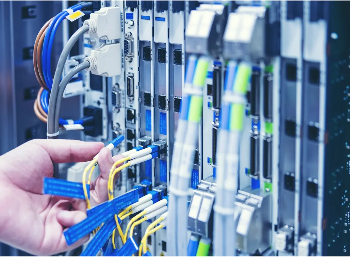 Technician connecting color-coded Ethernet cables to a network switch in a server rack, illustrating Ethernet cable colors and structured network standards