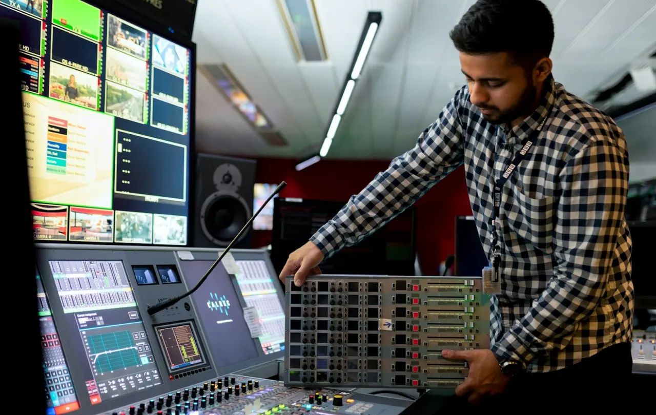 Broadcast audio control room with professional mixing console and audio processing equipment.