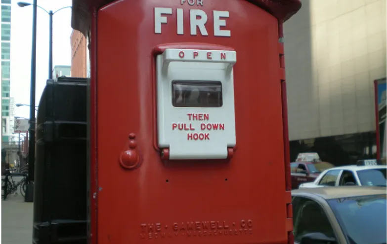 Red street fire alarm call box illustrating life safety emergency signaling infrastructure related to circuit integrity and 2-hour fire cable systems