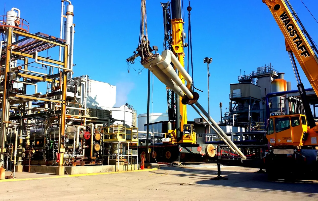 Industrial oil refinery with process piping and heavy machinery in harsh oil and gas environment.