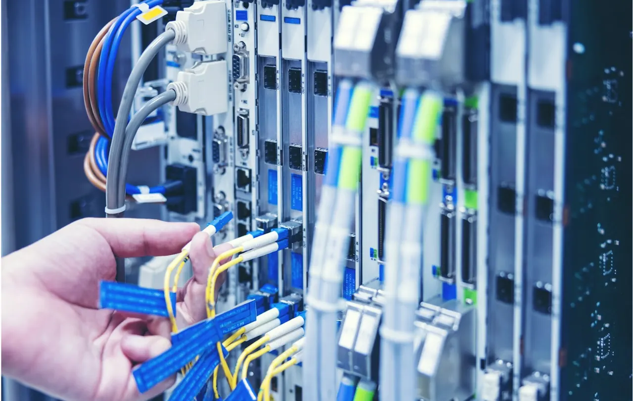 Technician connecting color-coded Ethernet cables to a network switch in a server rack, illustrating Ethernet cable colors and structured network standards